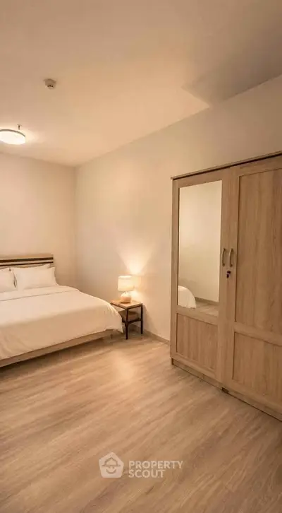 Spacious bedroom with wooden flooring and modern wardrobe in a cozy apartment.