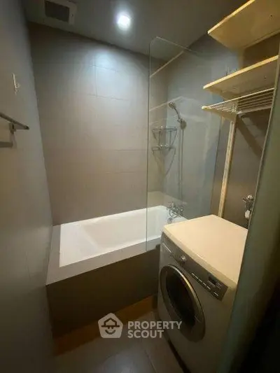 Compact bathroom with bathtub and washing machine in modern apartment.