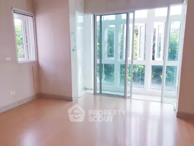 Bright empty room with large windows and wooden flooring, perfect for customization.