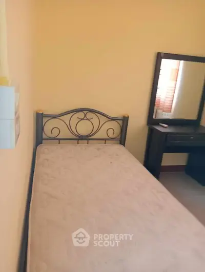 Cozy bedroom with single bed and vanity mirror in a warm-toned room.