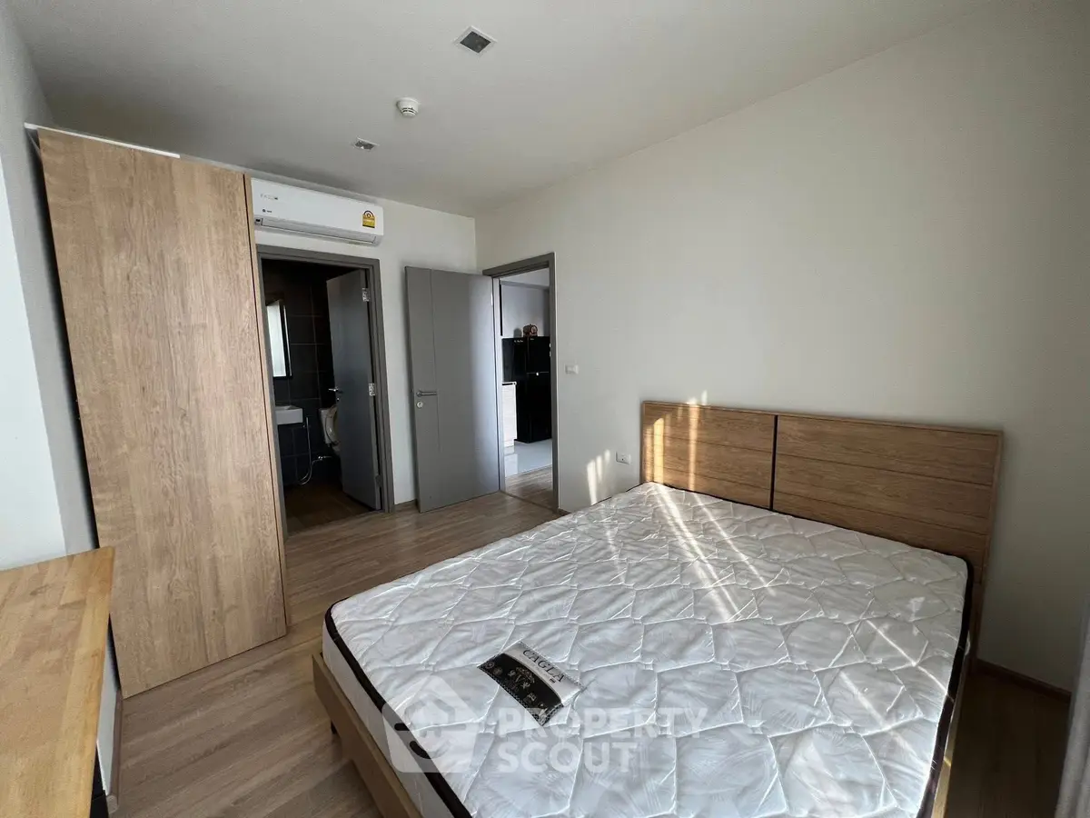 Modern bedroom with wooden flooring and built-in wardrobe, featuring a comfortable bed.