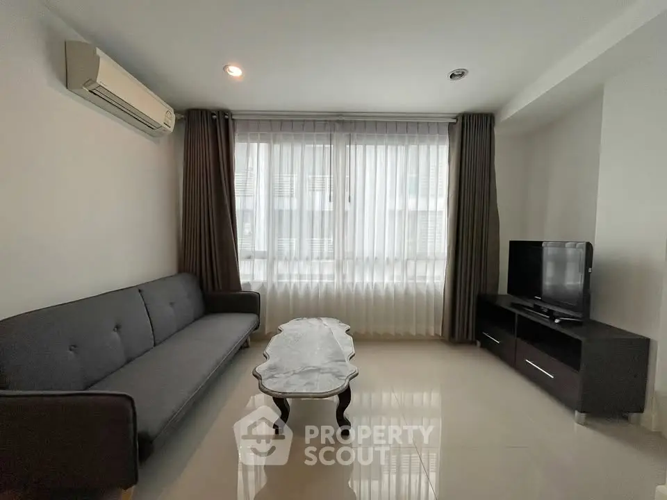 Modern living room with sleek furniture and large window, perfect for relaxation and entertainment.