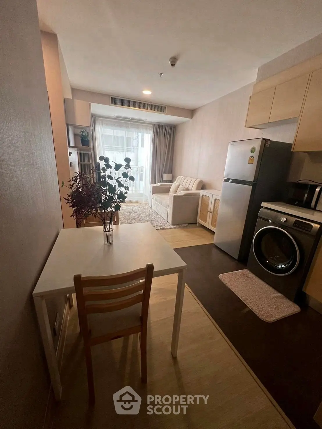 Cozy studio apartment with modern kitchen and living area, featuring a washing machine and fridge.