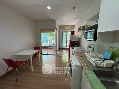 Modern open-layout kitchen and dining area with balcony view, featuring sleek appliances and wooden flooring.