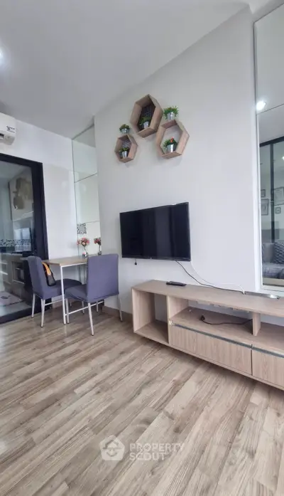 Modern living room with stylish decor and wooden flooring, featuring a wall-mounted TV and cozy dining area.