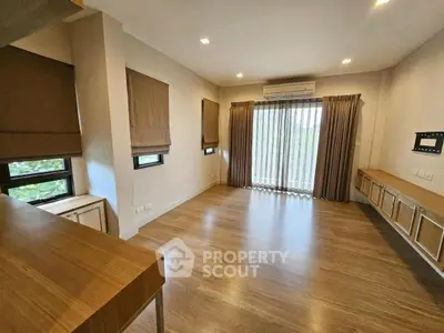 Spacious living room with wooden flooring and large windows for natural light.