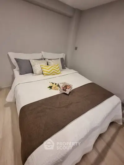 Cozy bedroom with stylish bedding and decorative pillows in modern apartment.