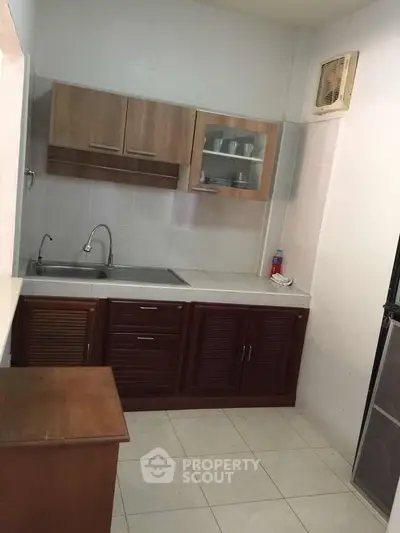 Compact kitchen with wooden cabinets and tiled flooring, featuring a closed layout.