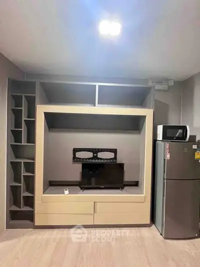 Modern living room with built-in TV unit and appliances, perfect for compact urban living.