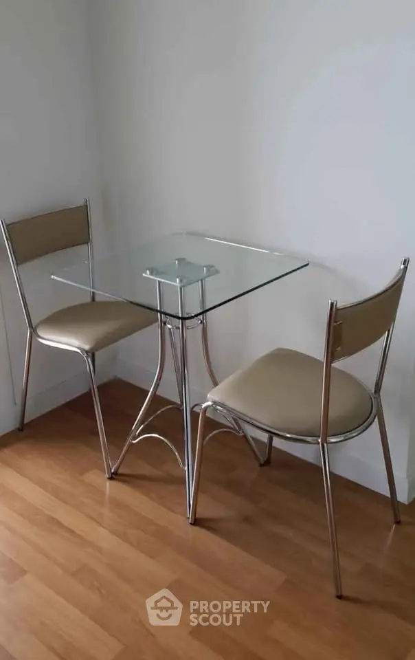 Modern dining nook with glass table and sleek chairs on wooden floor