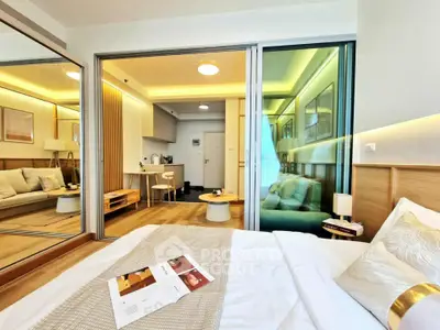 Modern bedroom with open layout to living area, featuring stylish decor and cozy ambiance.