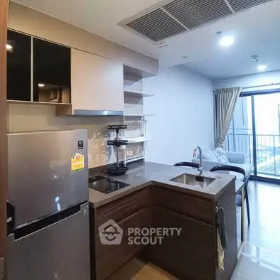 Modern kitchen with sleek design and open layout leading to a cozy living area with balcony view.
