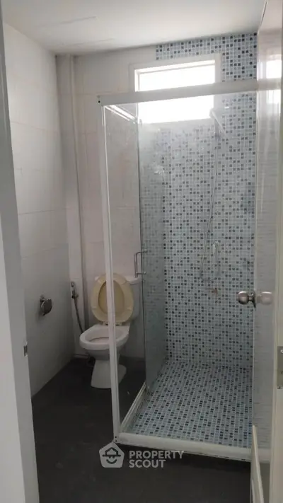 Modern bathroom with glass shower enclosure and tiled walls, perfect for a sleek urban apartment.