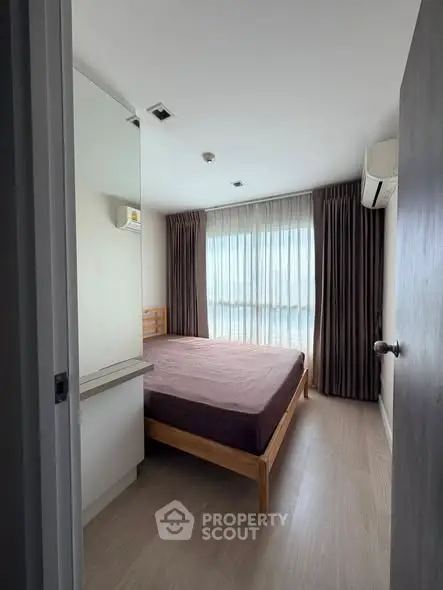 Cozy bedroom with large window and modern furnishings in a stylish apartment.