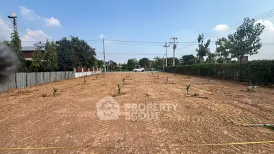 Expansive plot of land ready for development with clear skies and surrounding greenery.