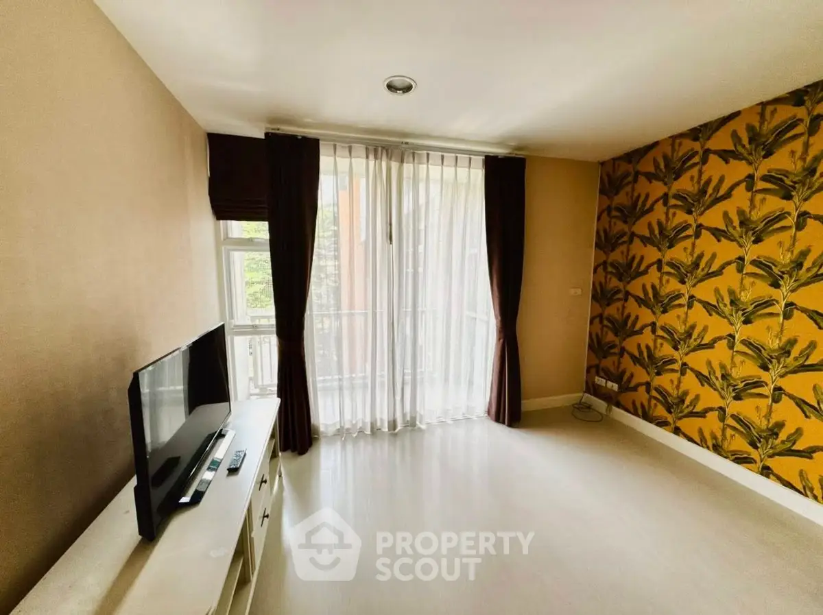Spacious living room with stylish wallpaper and natural light, perfect for modern living.