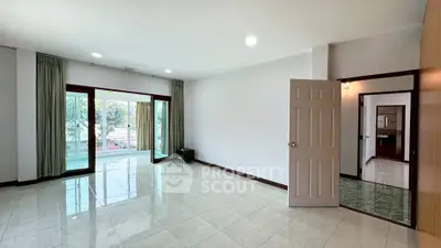 Spacious living room with large windows and glossy tiled floors, offering ample natural light and a serene view.