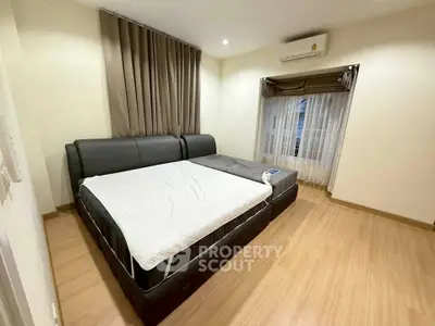 Spacious bedroom with modern decor and large bed, featuring wooden flooring and ample natural light.