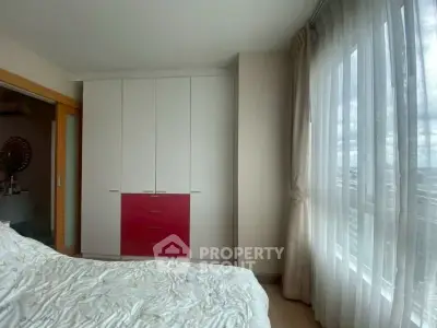 Bright bedroom with large window and modern wardrobe in a cozy apartment.
