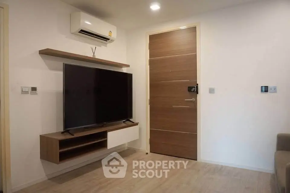 Modern living room with wall-mounted TV and air conditioning unit, featuring sleek wooden flooring and minimalist design.