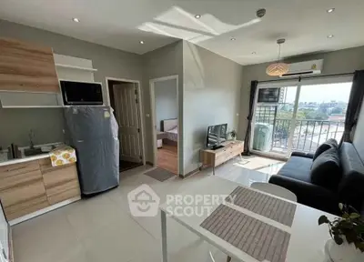 Modern open-plan living room with kitchen, featuring sleek furniture and natural light.