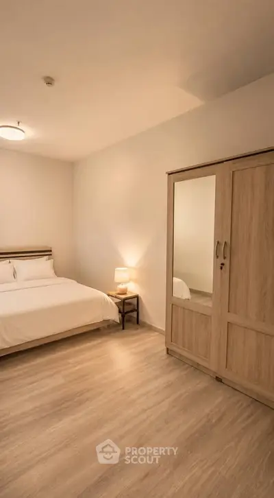 Spacious bedroom with wooden flooring and elegant wardrobe in modern apartment.
