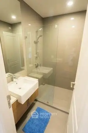 Modern bathroom with glass shower and sleek vanity in contemporary apartment.