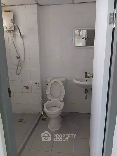 Compact bathroom with shower, toilet, and sink in minimalist design.