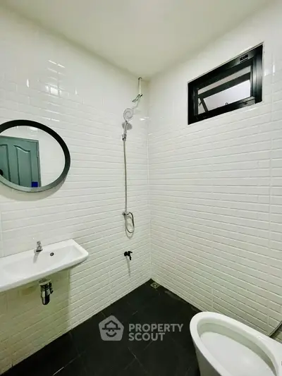 Modern minimalist bathroom with white tiles and sleek fixtures.
