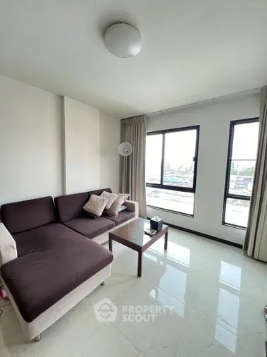 Bright and airy living space with glossy tiled flooring, comfortable sofa, and large windows offering an urban view, perfect for modern living.