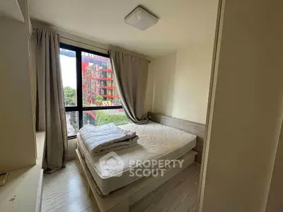 Cozy bedroom with large window and modern decor in urban apartment.