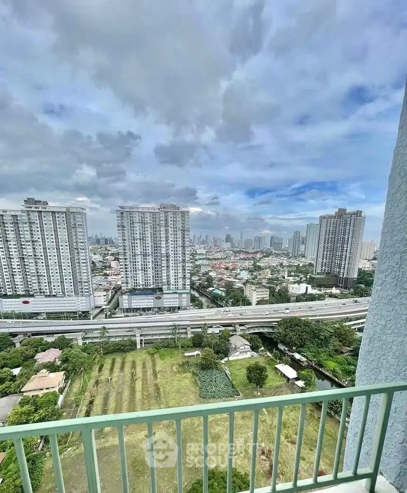 Stunning cityscape view from high-rise balcony with lush greenery and urban skyline.