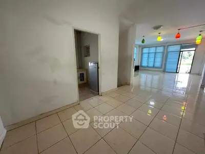 Spacious tiled living area with colorful pendant lights and large windows for natural light.