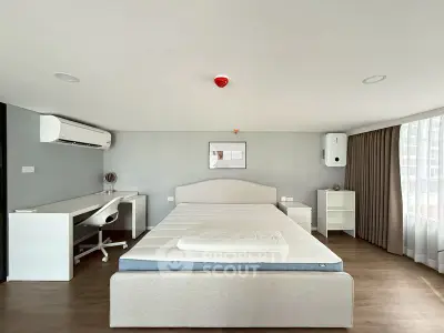 Modern bedroom with minimalist decor, featuring a large bed, desk, and ample natural light.
