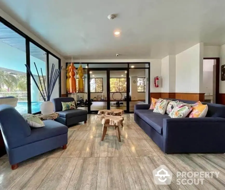 Spacious living room with modern decor and pool view, perfect for relaxation and entertaining.