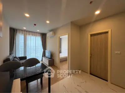 Modern living room with open layout and natural light, featuring sleek furniture and a view of the bedroom.