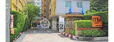 Modern condo entrance with lush greenery and secure access in vibrant urban setting.