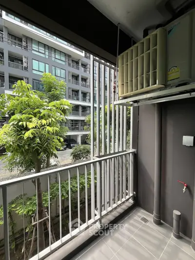 Modern apartment balcony with lush garden view and air conditioning unit.