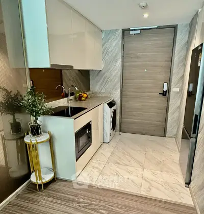 Modern kitchen with sleek cabinetry, built-in oven, and washing machine in a stylish apartment.