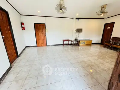 Spacious living room with tiled floor and minimal furniture, ideal for customization.
