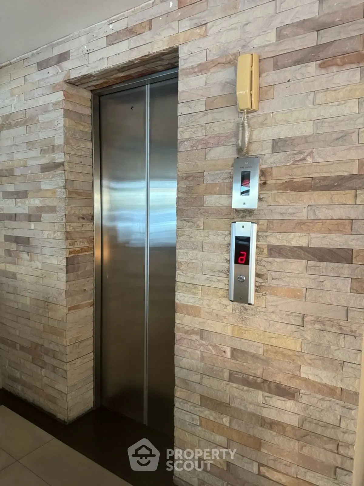 Modern elevator with stone wall design in a stylish building interior.