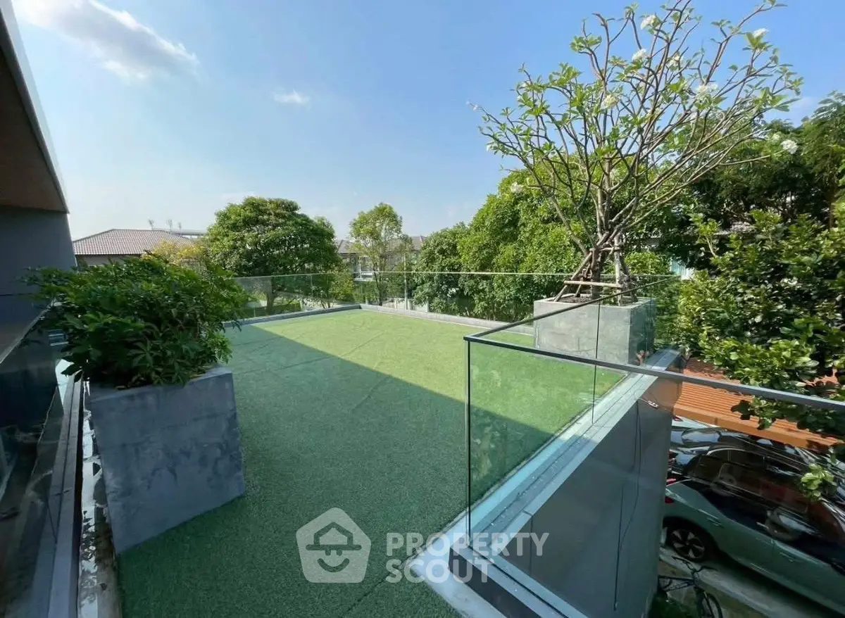 Stunning rooftop garden with lush greenery and glass railing, perfect for relaxation and outdoor enjoyment.