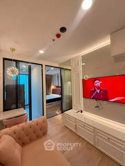 Modern living room with elegant decor and open view into a stylish bedroom, featuring a wall-mounted TV.