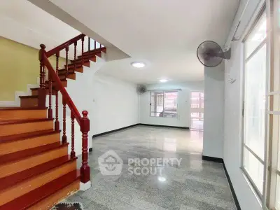 Spacious open-plan living area with elegant staircase and large windows