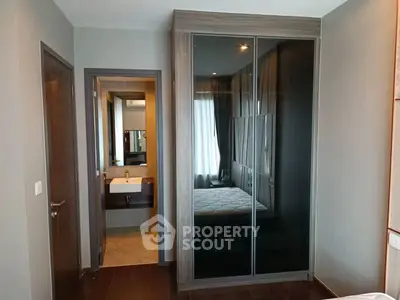 Modern bedroom with sleek wardrobe and ensuite bathroom in stylish apartment.