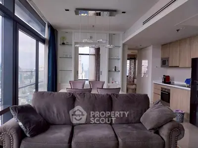 Luxurious modern living room with city view, elegant decor, and open kitchen layout.