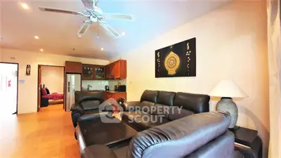 Spacious living room with leather sofas and modern decor in a cozy apartment.