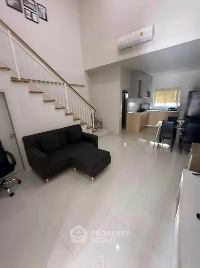 Modern open-plan living room with sleek kitchen and staircase