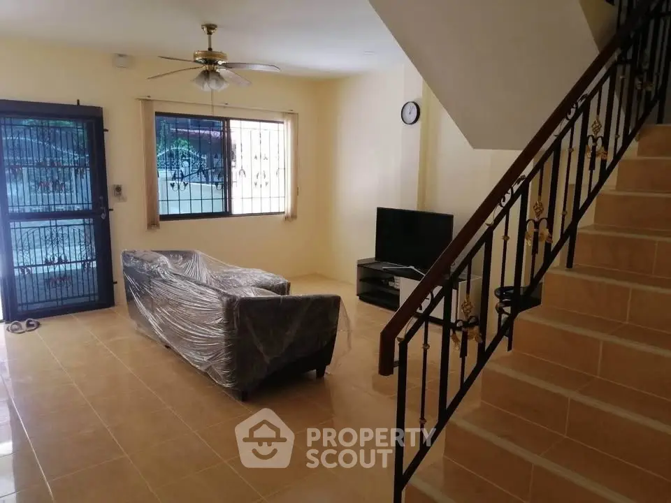Spacious living room with staircase and natural light, ideal for family gatherings.