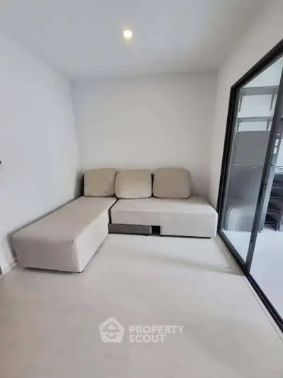 Modern minimalist living room with sleek sofa and sliding glass door.